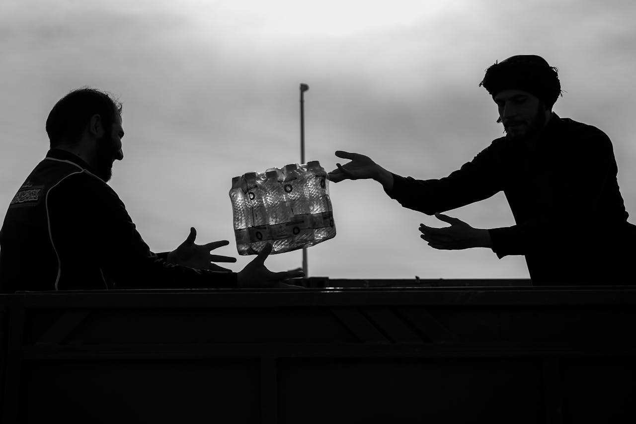 Man Passing Case of Bottles