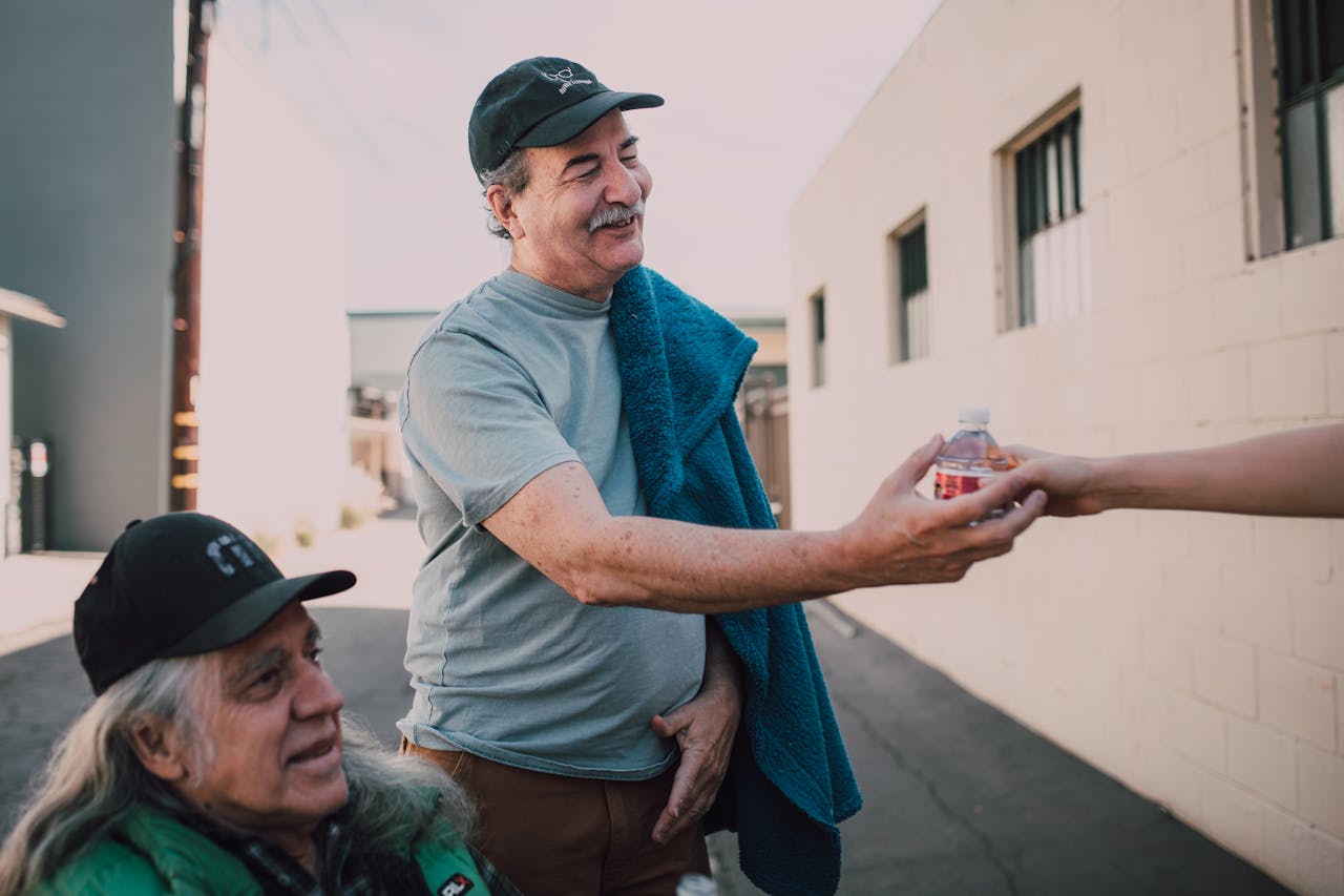 Elderly Man Wearing a Black Hat Receiving a Bottled Water